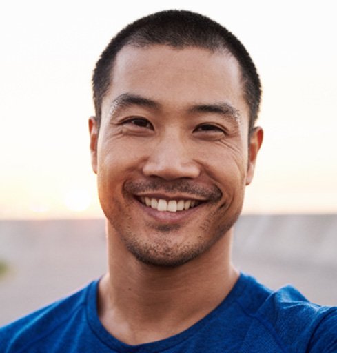 man smiling while taking selfie outside 