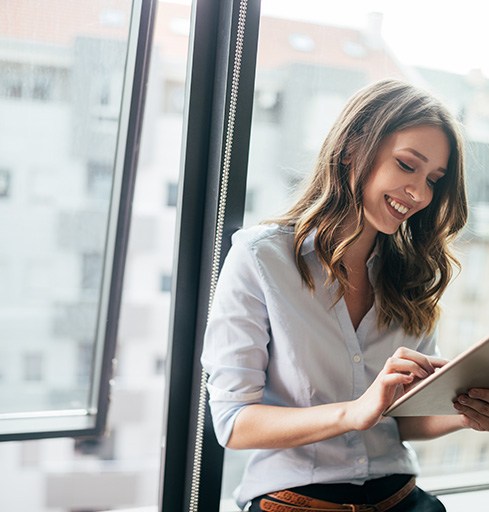 Woman sitting by window, working on tablet