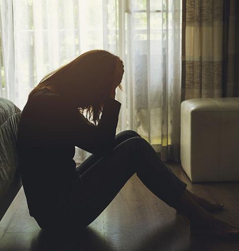 young woman with depression sitting with heads in hands