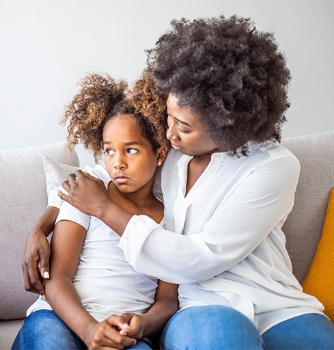 Girl with anxiety, being comforted by her mother