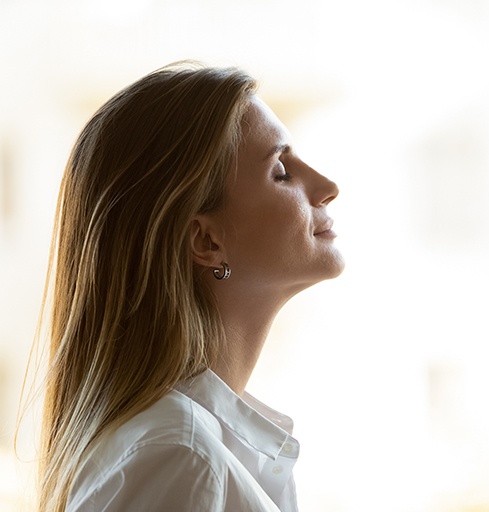 Woman taking a deep breath, wearing peaceful expression
