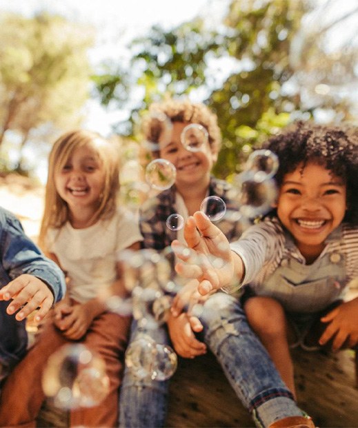 Happy kids playing with bubbles outdoors