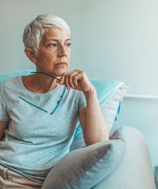 a woman holding her glasses and looking off to the side