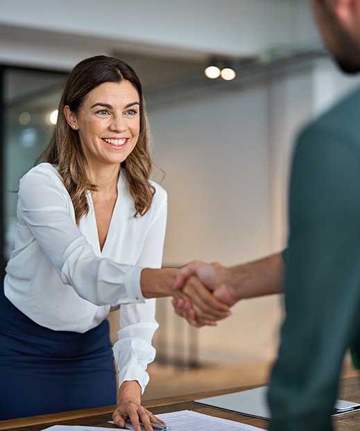 Two people shaking hands across a desk
