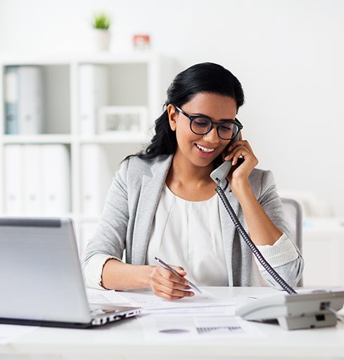 Woman sitting behind desk, talking on phone
