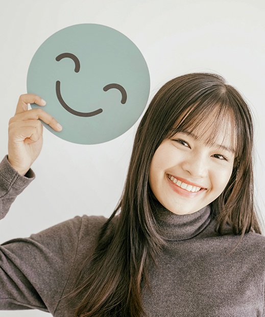 Hapy woman holding smiley face sign