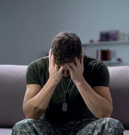 Soldier sitting on sofa, struggling with PTSD symptoms