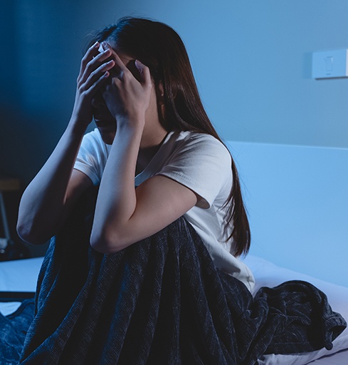 Woman sitting up in bed after PTSD nightmare