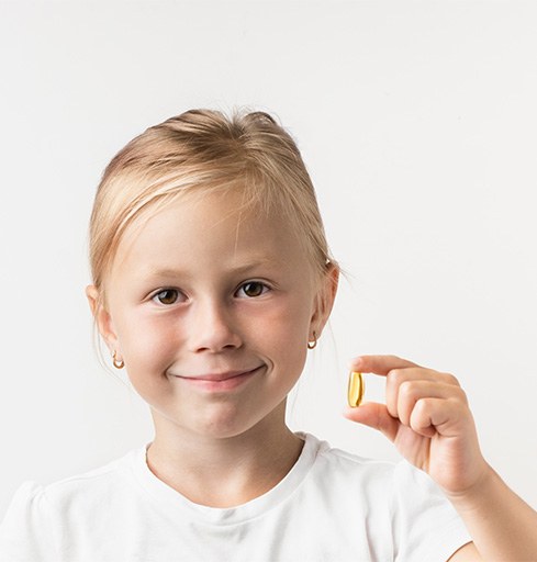 Smiling girl holding supplement pill