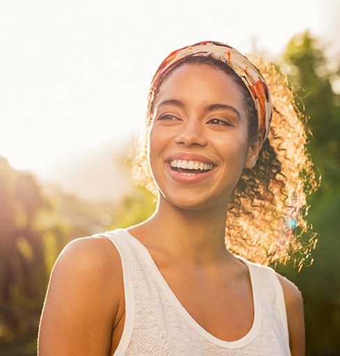 young woman smiling while standing outside 