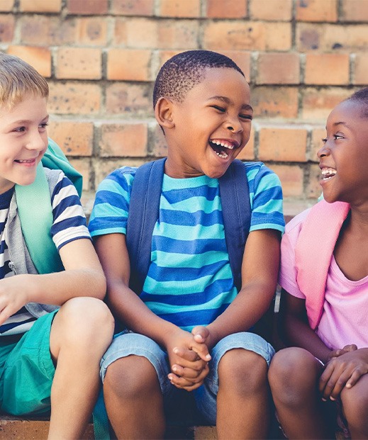 Three happy children wearing school backpacks