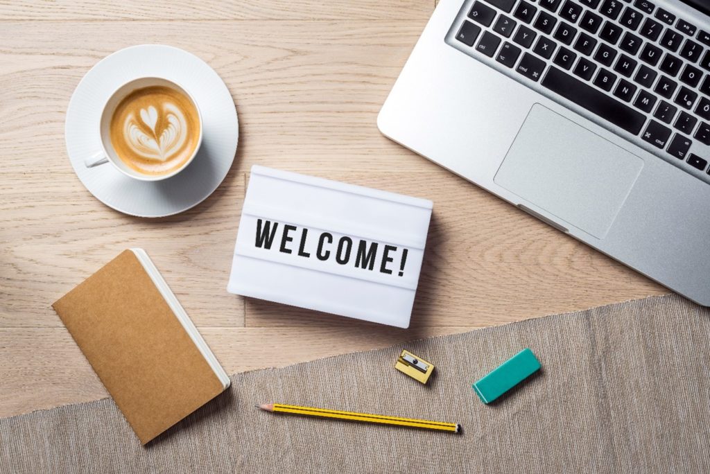 Welcome sign lying on table with computer and desk supplies