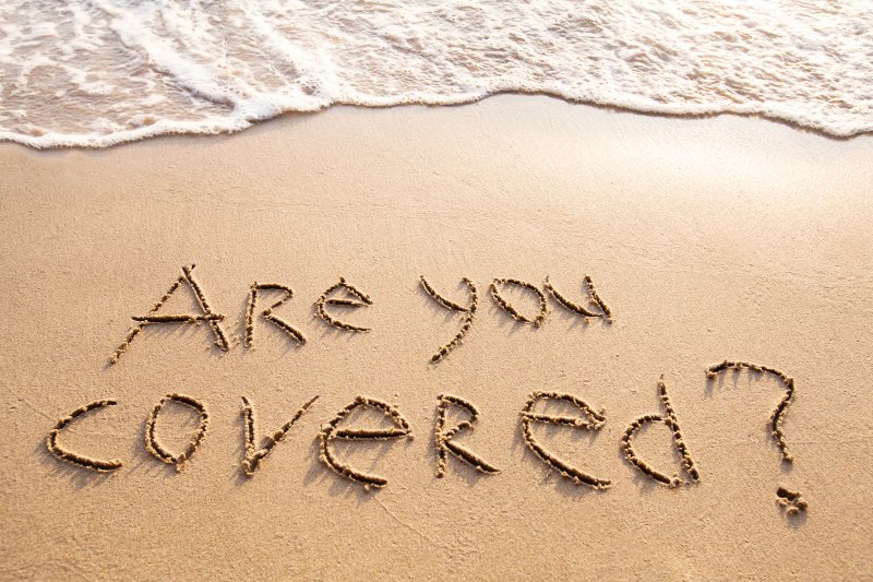 a beach shore with sand that spells are you covered	