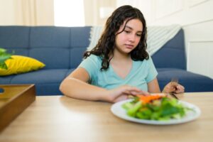 Teen girl pushing away her dinner plate