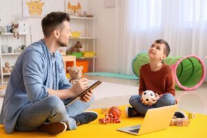 Young boy holding toy while talking to therapist