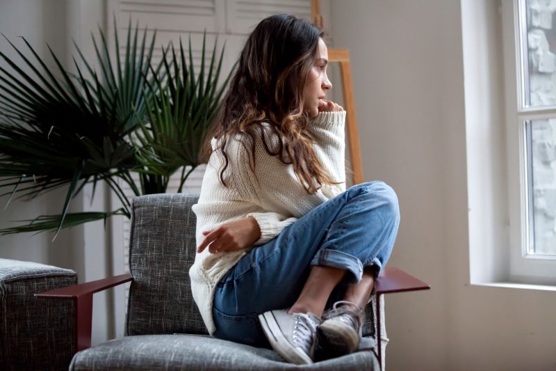 Anxious depressed young woman looking out the window