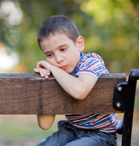 sad boy sitting on park bench v1